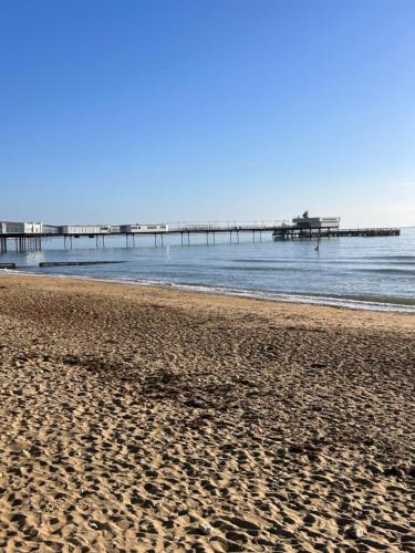 a sandy beach with a pier in the water at The Bay house Apartments , shanklin in Shanklin