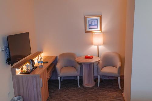 a room with two chairs and a table and a tv at La Casa Hotel Amman by FHM in Amman