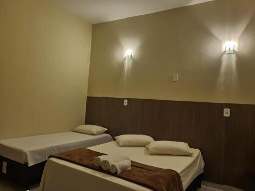 two beds in a room with two lights on the wall at Pousada Rancho Bonito in Bonito