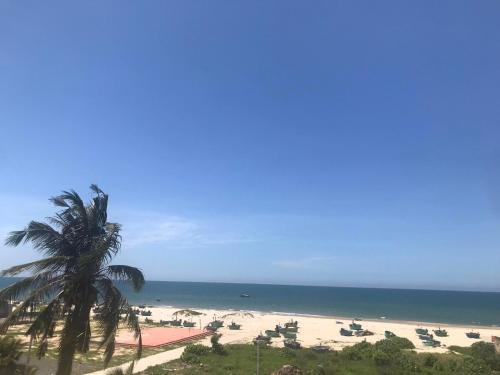 een uitzicht op een strand met een palmboom en de oceaan bij Nhà Nghỉ Ngọc Ánh in Ấp Tam Tân