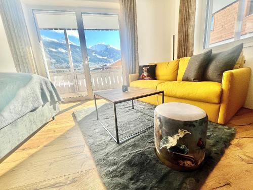 a living room with a yellow couch and a table at Auhof - Apartments Bad Gastein in Bad Gastein