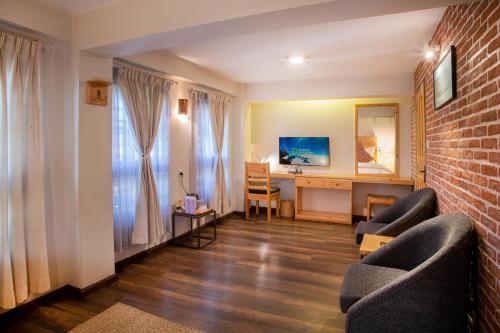 a living room with a desk and chairs and a brick wall at Hotel Timila in Pātan