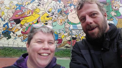 a man and a woman standing in front of a mural at 14-18 Somme Chambres in Beaucourt-sur-lʼAncre