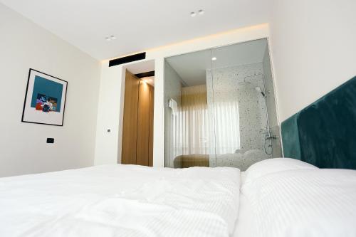 a bedroom with a white bed and a large mirror at HOTEL 12 in Gjakove