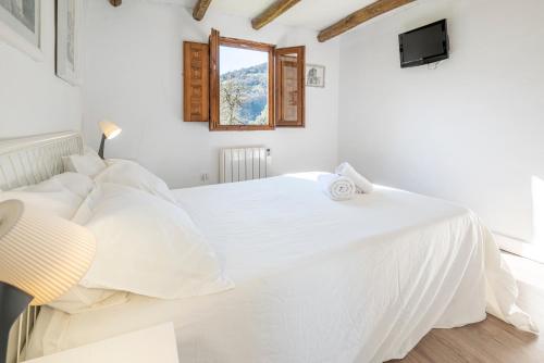 a white bedroom with a white bed and a window at Casa Rafa in Buellas