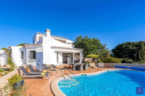 a villa with a swimming pool in front of a house at Casa Carob in Lagoa
