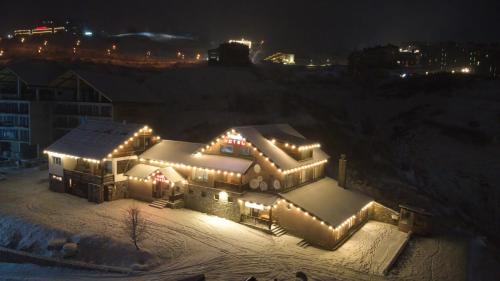 a house covered in lights in the snow at night at Hotel Truso in Gudauri