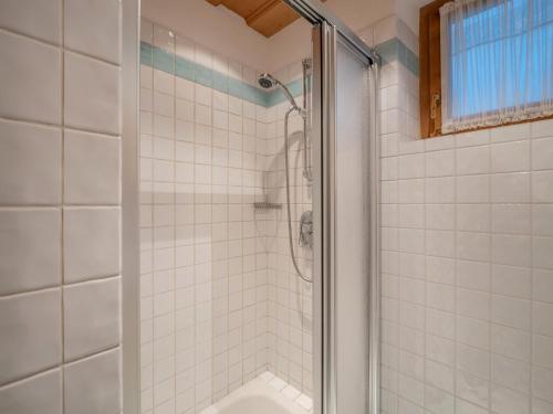 a white tiled shower with a glass door at Landhaus Ammer in Oberndorf in Tirol