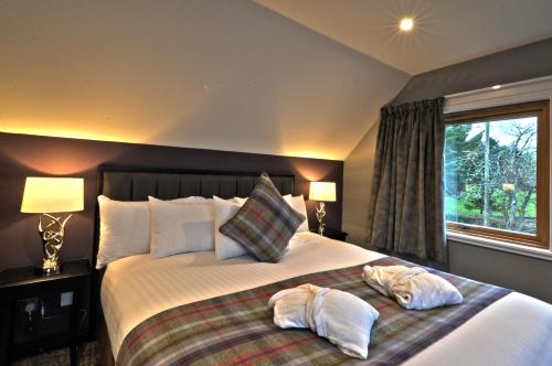 a bedroom with a large bed with two pillows on it at The Beach House Loch Lomond in Luss