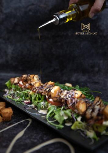 a person sprinkling sauce on a plate of food at Hotel Mondo in Split
