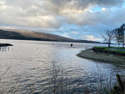 a large body of water with mountains in the background at The Beach House Loch Lomond in Luss