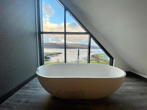 a large bath tub in a room with a large window at The Beach House Loch Lomond in Luss