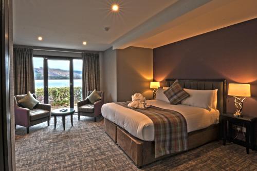 um quarto de hotel com uma cama e uma grande janela em The Beach House Loch Lomond em Luss