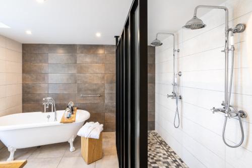 a bathroom with a tub and shower and a sink at Les Jardins de Coppélia in Pennedepie