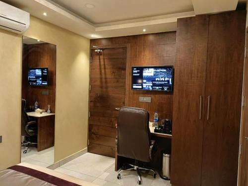 a hotel room with a desk and a tv on a wall at Retrieve Health & Wellness in Cochin