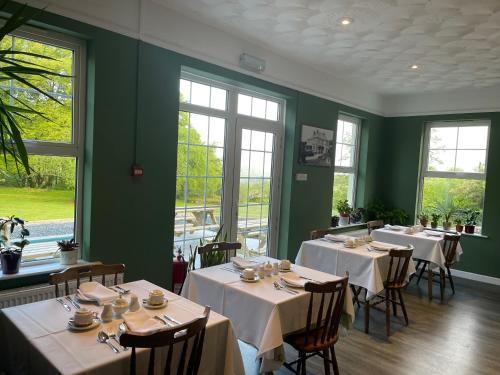 ein Esszimmer mit Tischen, Stühlen und Fenstern in der Unterkunft Moorlands in Parracombe