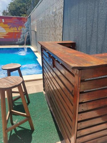 a wooden bar with a stool next to a swimming pool at Casa com Piscina e 3 Quartos Climatizados 8km do Centro in Palmas