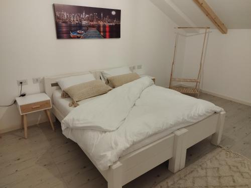 een wit bed in een kamer met een schilderij aan de muur bij סוויטת בוטיק in Netivot