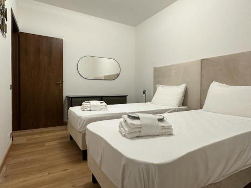 2 bedden in een hotelkamer met een spiegel bij Due Carrare Business in Due Carrare