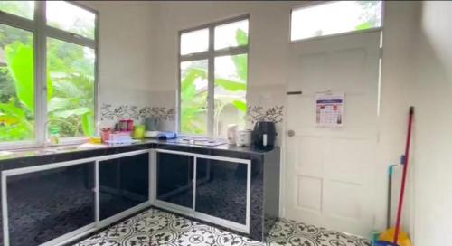a kitchen with a counter and a sink and windows at Amy Homestay-Suasana kampung yang nyaman in Pasir Mas