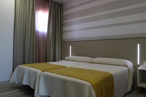 a bedroom with a large bed with a striped wall at Hotel Leo in Monesterio