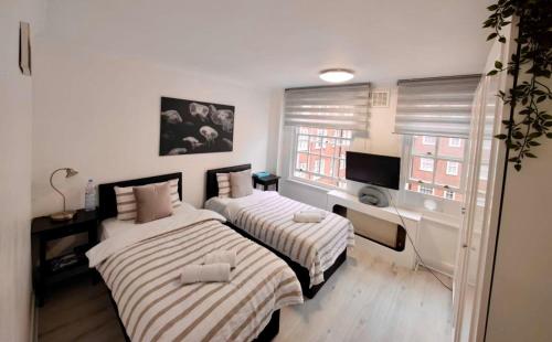 2 camas en una habitación pequeña con ventana en Park West Apartment, en Londres