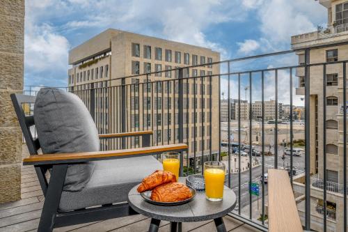 een balkon met een tafel met eten en sinaasappelsap bij prestige 2BDR&2Bth w Parking- mahne yehuda sea-u jerusalem in Jeruzalem
