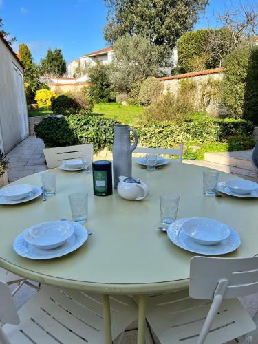 - une table blanche avec des assiettes et des verres dans l'établissement Le Richelieu - Cocon familliale, à La Rochelle