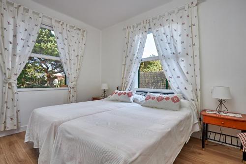 a white bedroom with a bed and two windows at Las Sabinas Playa - El Guincho, Garachico in Garachico