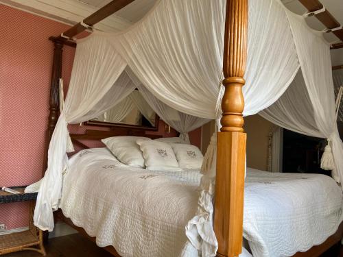 a bedroom with a canopy bed with white sheets and pillows at Grellsbo in Grebbestad