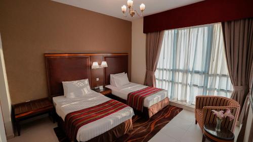 a hotel room with two beds and a window at Xclusive Hotel Apartments in Dubai