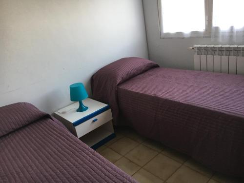 twee bedden in een kamer met paarse bedden en een lamp bij Fiordaliso in Minturno