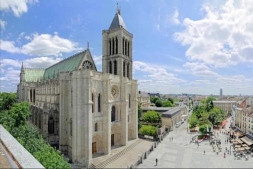 duży budynek z wieżą zegarową na górze w obiekcie LE COSY de Saint-Denis w mieście Saint-Denis