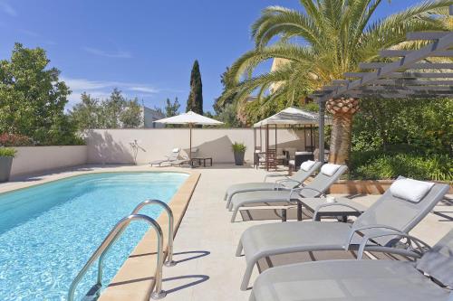 a pool with lounge chairs and umbrellas next to it at Guesthouse Palma - Suite Arabella Apartment, Adults Only in Palma de Mallorca