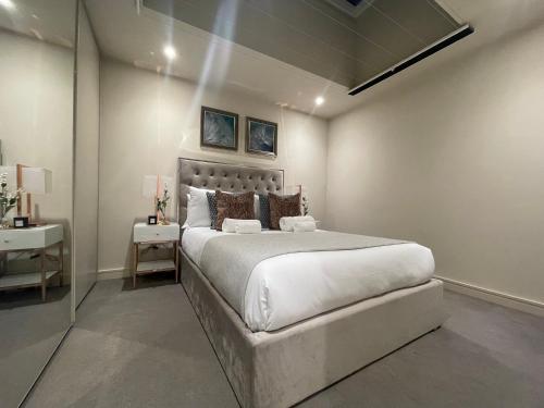 um quarto com uma cama grande e uma mesa lateral em Sophisticated 1BR, 1 BA Chigwell Designer Flat CHCL F2 em Chigwell