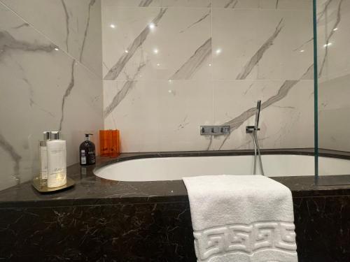 a bathroom with a bath tub with a towel on a counter at Sophisticated 1BR, 1 BA Chigwell Designer Flat in Chigwell