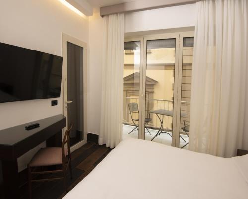 sypialnia z łóżkiem i telewizorem oraz balkonem w obiekcie Domus Altana w mieście Napoli