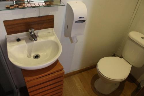 a bathroom with a white toilet and a sink at Hostal Queltehue in Ancud