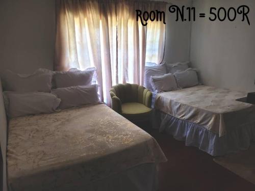 a room with two beds and a chair and a window at PRIME GUEST HOUSE in Boksburg