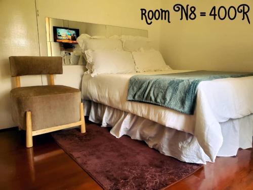 a bedroom with a bed and a chair and a tv at PRIME GUEST HOUSE in Boksburg