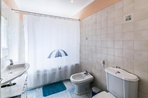 y baño con aseo, lavamanos y sombrilla. en Villa Quinta da Marinha II en Cascais