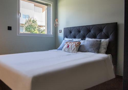 a large white bed with a large headboard and a window at Thyrso Village in Santo Tirso