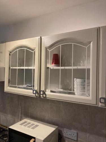 a kitchen with white cabinets with glass windows at Lovely 2 Bed House Apartment in Boston TownCentre in Boston