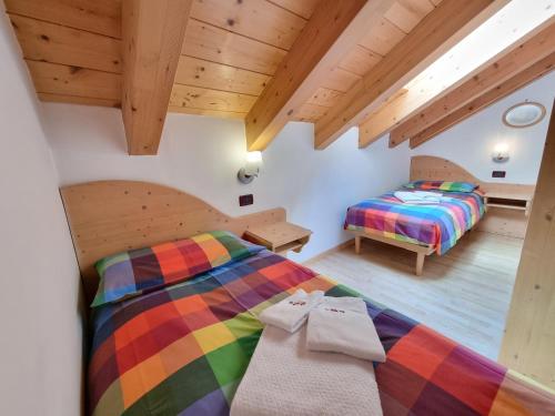 2 letti in una camera con soffitti in legno di Residence Le Rose a Pozza di Fassa