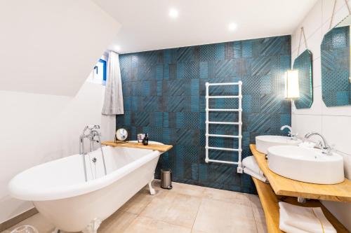 two sinks and a tub in a bathroom with blue tiles at Les Jardins de Coppélia in Pennedepie