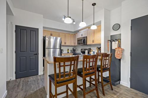 a kitchen with a bar with chairs and a refrigerator at Mountain Retreat - Modern and Bright with Panorama Views 2 bedrooms, 4 beds, heated all-year outdoor pool, hottub, balcony, Banff Park Pass in Canmore