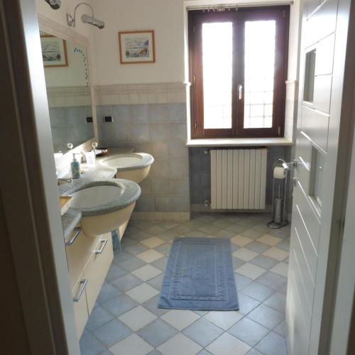 een badkamer met 2 wastafels, een bad en een raam bij Cartune' in Verzuolo