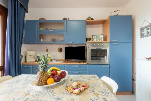 kuchnia z niebieskimi szafkami i stołem z misą owoców w obiekcie AffittaSardegna-CASA SERSE w mieście Stintino