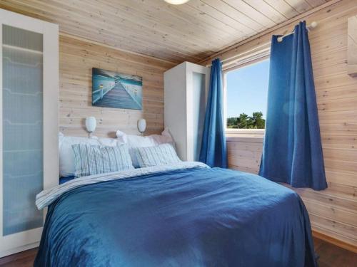 Un dormitorio con una cama azul y una ventana en Holiday home TORANGSVÅG II, en Skår