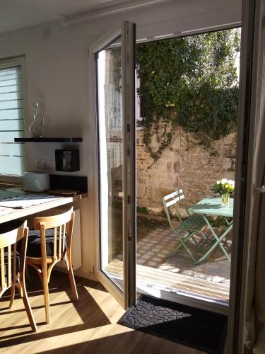 une porte menant à une terrasse avec une table et des chaises. dans l'établissement Le Duclos, appartement rez-de-jardin Dinan centre, à Dinan